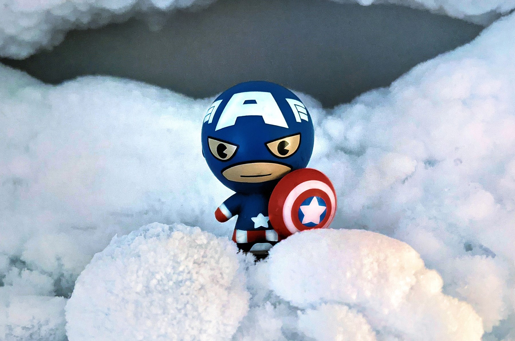 Figur im Schnee, Heldenfigur, rot-blauer Avenger mit Schutzschild im Schnee, Kampf gegen die Kälte, Schneebeseitigung, Winterdienst