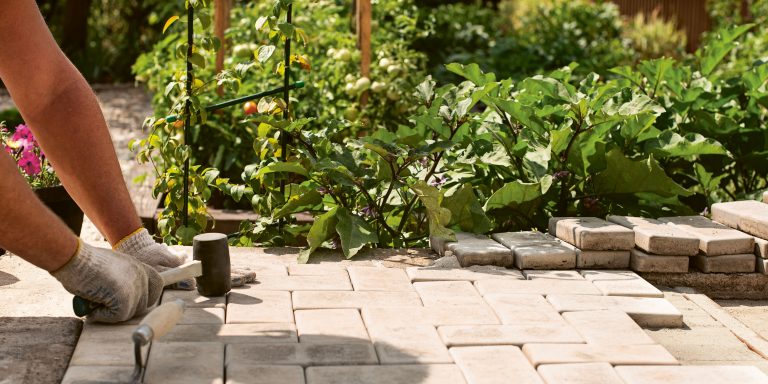 Gartengestaltung, Natursteinarbeiten, Garten- und Landschaftsbau, Mitarbeiter verlegt Steine für Wegegestaltung im Garten